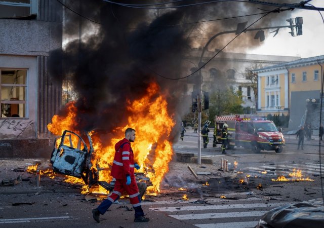 Záchranář prochází kolem auta zničeného ruským raketovým útokem na Kyjev 10. října 2022.