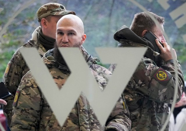 Návštěvníci ve vojenské kamufláži stojí u vchodu do „PMC Wagnerova centra“, které je spojeno s podnikatelem a zakladatelem soukromé vojenské skupiny Wagner Jevgenij Prigožin, během oficiálního otevření kancelářského bloku během Dne národní jednoty v St. Petersburg, Rusko, 4. listopadu 2022.