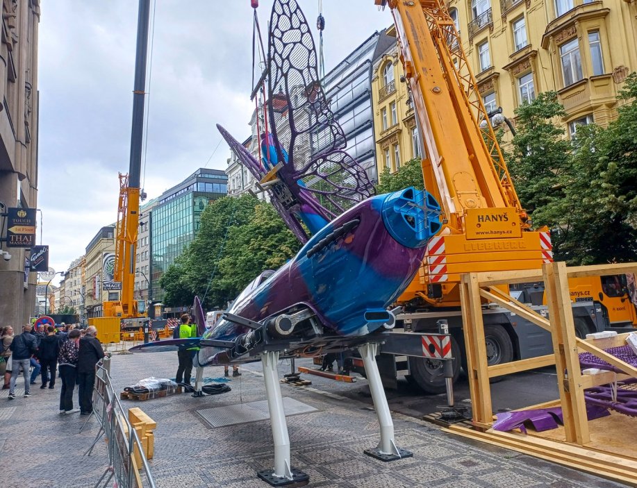 Na obchodní dům Máj na pražské Národní třídě dělníci instalují několikametrové motýly od výtvarníka Davida Černého s trupem napodobujícím stíhačku spitfire