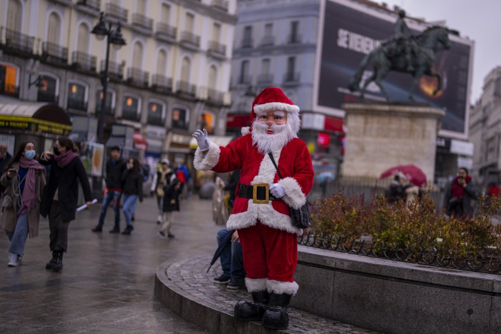 Muž v převleku Santa Clause mává na kolemjdoucí na Sol square v Madridu. Na rozdíl od turistů i místních má výjimku a nemusí mít na tváři roušku.