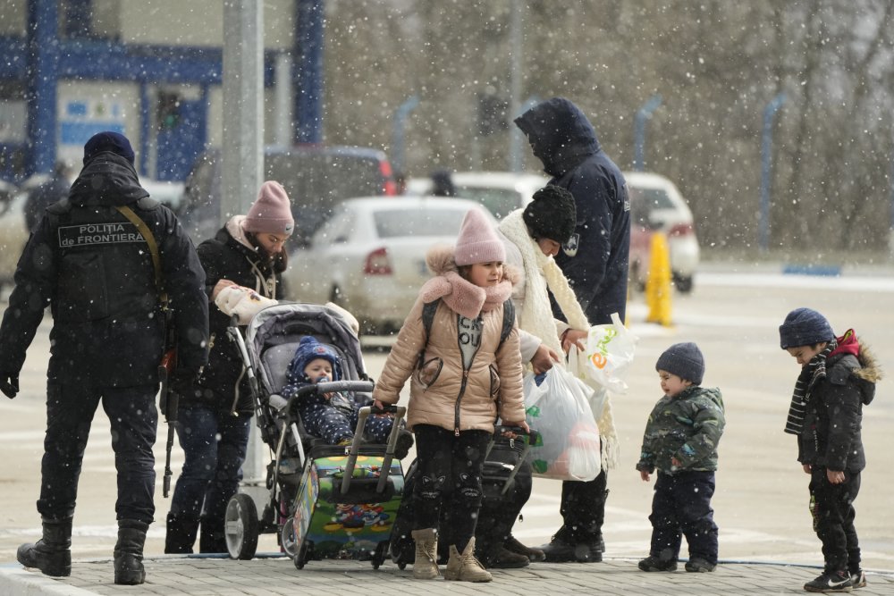 Pohraničníci kontrolují ukrajinskou rodinu prchající z Ukrajiny na přechodu v moldavské Palance, 11. března 2022